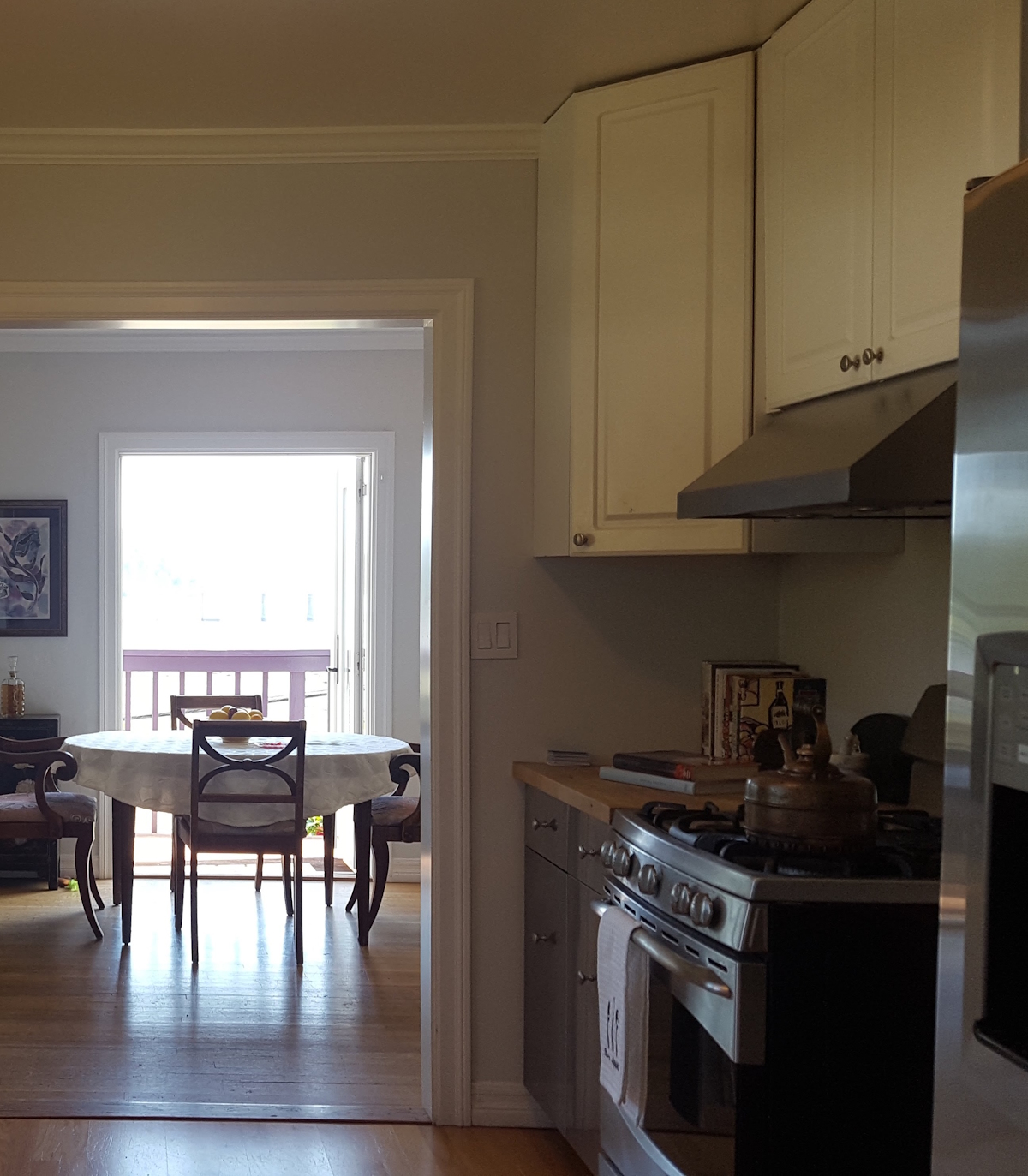A kitchen with white cabinets, a stove, and a table in the adjoining dining room