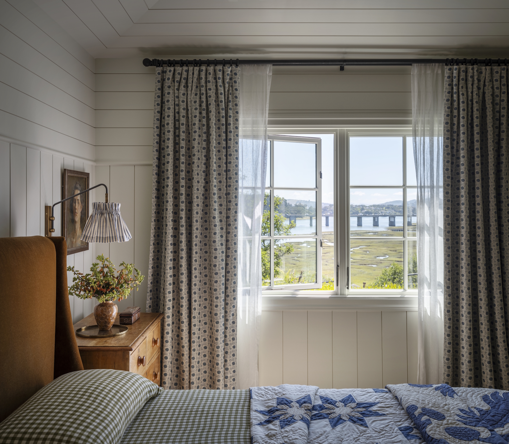 A bedroom window view showing an open window with patterned curtains