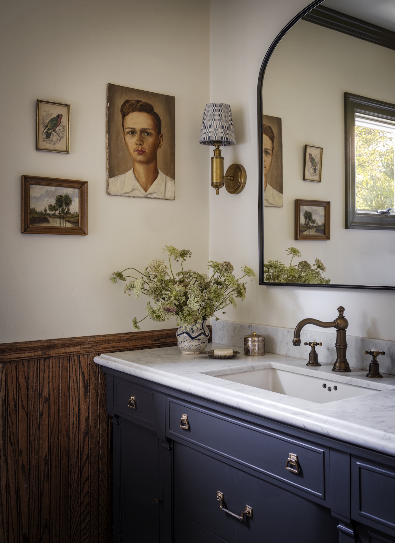 A bathroom vanity with sink and a mirror and art on the walls
