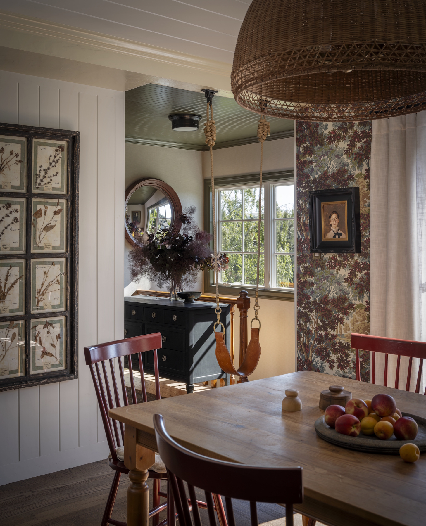 A dining room featuring a swing, large light fixture, window to the outdoors, and flowered art decor